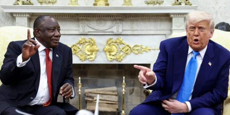 Two officials seated in a formal meeting room, gesturing during a discussion with a model aeroplane on the table between them