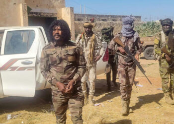 Abu Lulu (left), an RSF fighter reportedly seen in execution videos from El-Fasher, stands under guard by fellow paramilitaries in North Darfur after his arrest.
