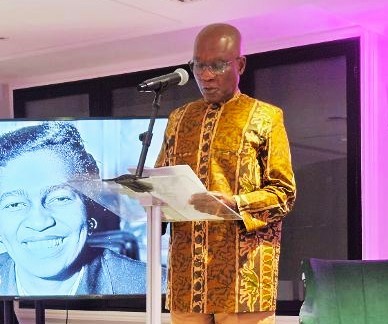 Dr Akyaaba Addai-Sebo delivers a lecture in London’s Camden during Black History Season, standing at a podium beside an image of Claudia Jones.