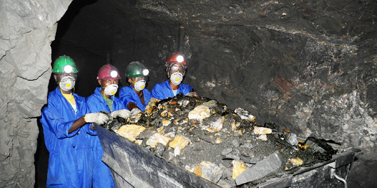 Miners wearing protective gear work underground in Cote d’Ivoire, extracting mineral-rich ore during exploration for lithium and other critical minerals.