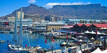 Cape Town’s V&A Waterfront with Table Mountain in the background on a clear summer day, showing boats, shops and visitors