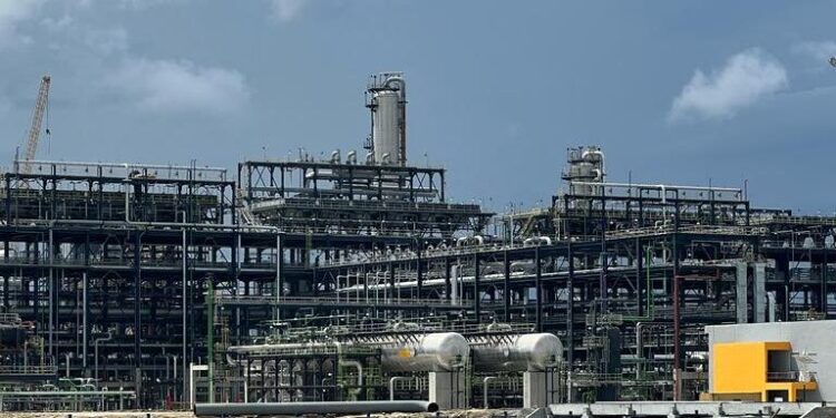 Exterior view of Dangote Refinery complex showing large industrial structures, pipelines and processing units under a cloudy sky