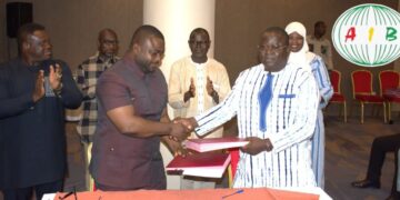 Officials from Ghana and Burkina Faso shake hands during the signing of a new free mobile roaming agreement in Ouagadougou, as other delegates applaud