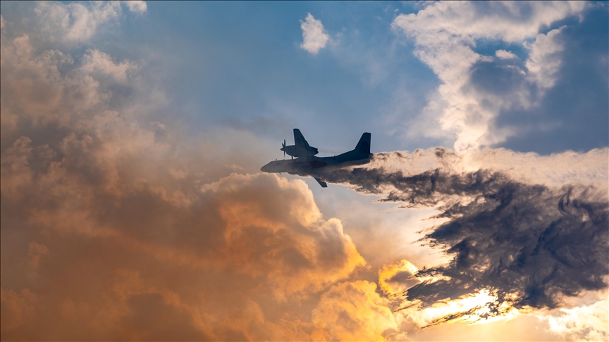 A twin-engine aircraft flying through dramatic clouds with dark smoke trailing from one side during an in-air emergency.
