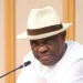A Nigerian government minister wearing a white hat and shirt speaks into a microphone during a meeting in Abuja.
