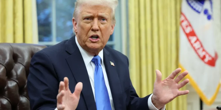 US President Donald Trump speaking during a meeting in the Oval Office, gesturing with both hands while addressing reporters.