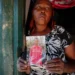 A woman stands in a doorway holding a photograph of her younger sister, Agnes Wanjiru, who was allegedly murdered in Nanyuki, Kenya, in 2012.
