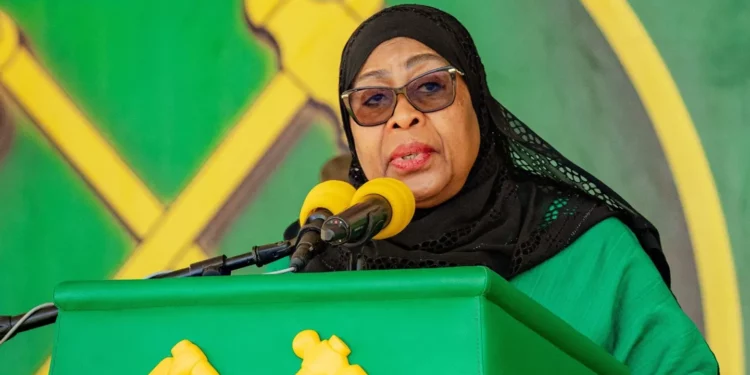 Tanzania’s President Samia Suluhu Hassan speaking at a podium during a public address, wearing a black headscarf and green attire.