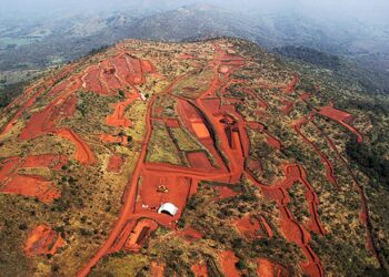 Excavators working on a red-earth hillside at the Simandou iron-ore project in Guinea