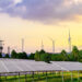 Solar panels and wind turbines generating renewable energy at sunset in a semi-rural landscape.