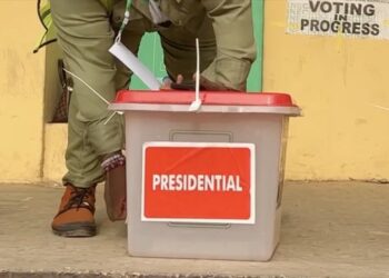 An election officer handling a sealed ballot box labelled ‘Presidential’ during voting at a polling station in Tanzania