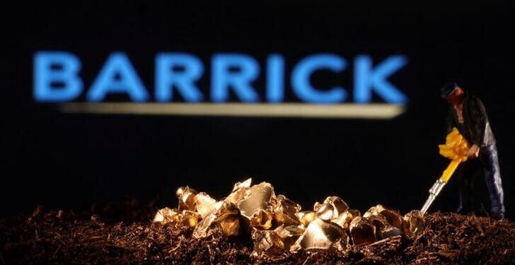 A miniature figure works beside a small pile of gold nuggets with the Barrick company logo blurred in the background.