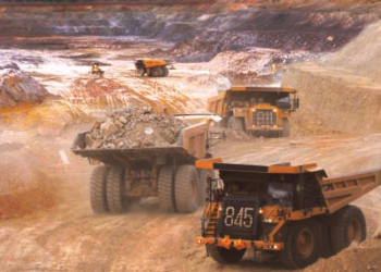 Large haul trucks transporting ore at an open-pit mining site in Burkina Faso.
