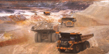Large haul trucks transporting ore at an open-pit mining site in Burkina Faso.