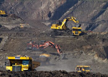 A wide view of heavy mining machinery and dump trucks operating in an open-pit coltan mine in the Democratic Republic of the Congo