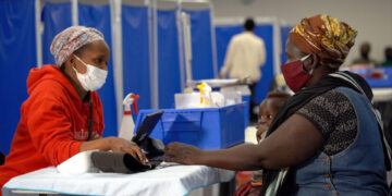 A health worker speaks with a mother and child at a public clinic in Eswatini, highlighting ongoing challenges in the country’s healthcare system.