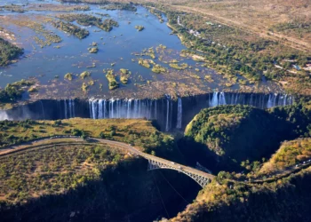 Aerial view of Victoria Falls, Zimbabwe, showing cascading water and lush green surroundings along the Zambezi River.