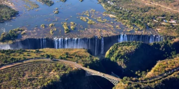 Aerial view of Victoria Falls, Zimbabwe, showing cascading water and lush green surroundings along the Zambezi River.