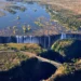 Aerial view of Victoria Falls, Zimbabwe, showing cascading water and lush green surroundings along the Zambezi River.
