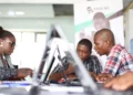 A group of young African tech entrepreneurs working on laptops in a co-working space during a start-up programme