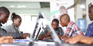 A group of young African tech entrepreneurs working on laptops in a co-working space during a start-up programme