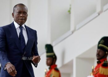 Benin’s President Patrice Talon walks past ceremonial guards in uniform at a government building.