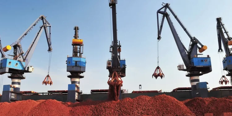 Bauxite ore being loaded by cranes at a port facility in Guinea, the world’s largest bauxite producer