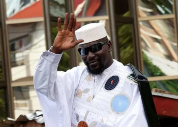 Guinea’s president Mamady Doumbouya waves while wearing traditional attire and sunglasses during a public appearance in Conakry