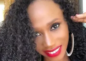 Smiling woman with long curly hair and red lipstick, wearing hoop earrings