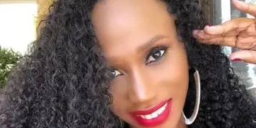 Smiling woman with long curly hair and red lipstick, wearing hoop earrings