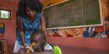 A teacher helps a young pupil write in class at Atsikana Pa Ulendo Girls Secondary School near Lilongwe, Malawi.