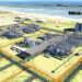 Aerial rendering of the Mozambique LNG project showing gas-processing facilities, storage tanks and coastal infrastructure along the Cabo Delgado shoreline