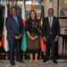 Three executives stand side by side in a formal setting with African national flags behind them at an aviation meeting.