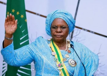 Namibia’s President Netumbo Nandi-Ndaitwah raises her hand during an official ceremony, wearing a blue traditional outfit and ceremonial honours