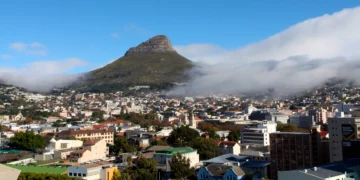 A panoramic view of Cape Town with Lion’s Head mountain rising above the city on a clear day, with low clouds rolling over the slopes
