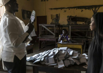 Vote counting underway inside a polling station in Guinea as election officials sort ballot papers following the presidential vote
