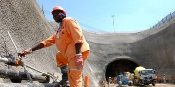Construction worker in protective gear stands beside pipes at the entrance of the Gautrain underground tunnel in Gauteng, South Africa