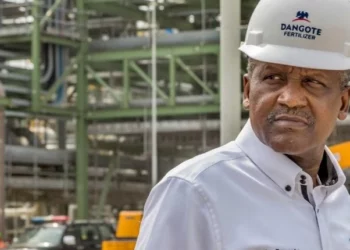 Aliko Dangote wearing a hard hat at a fertiliser plant, inspecting industrial equipment