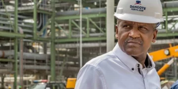 Aliko Dangote wearing a hard hat at a fertiliser plant, inspecting industrial equipment