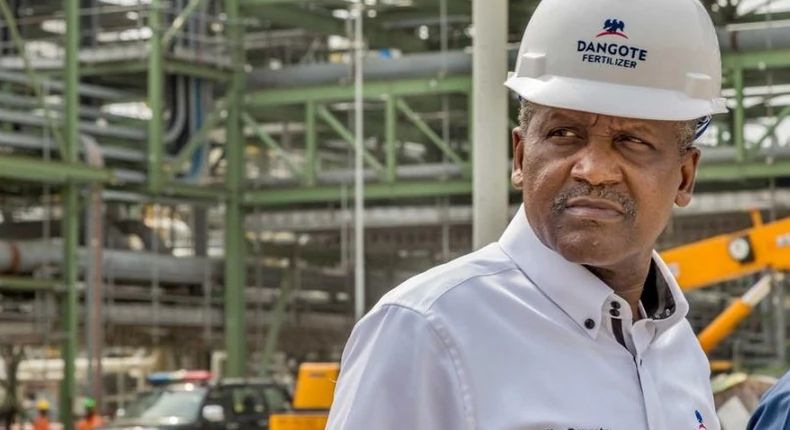 Aliko Dangote wearing a hard hat at a fertiliser plant, inspecting industrial equipment