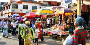 Busy market scene in Ghana with traders, shoppers and colourful stalls reflecting local economic activity