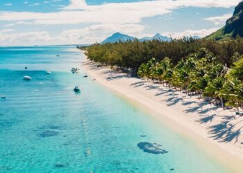 Aerial view of Mauritius coastline with white-sand beach, turquoise Indian Ocean waters and palm-lined shore