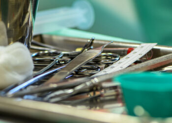 Surgical instruments, scalpels and gauze on a metal tray during a medical procedure