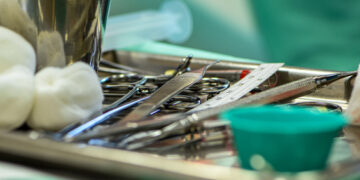 Surgical instruments, scalpels and gauze on a metal tray during a medical procedure