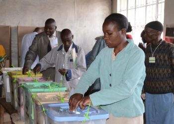 Voters in Kenya casting ballots during a by-election at a polling station, placing papers into colour-coded ballot boxes.