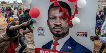 Supporters gather around a damaged Bobi Wine campaign poster during an opposition rally in Uganda ahead of the 2026 election