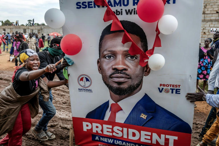 Supporters gather around a damaged Bobi Wine campaign poster during an opposition rally in Uganda ahead of the 2026 election