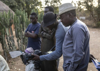 Northern Nigerian filmmakers review footage on set in Kano, highlighting the low-budget realities of Kannywood productions compared with southern Nigeria’s Nollywood