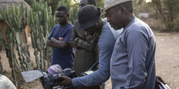 Northern Nigerian filmmakers review footage on set in Kano, highlighting the low-budget realities of Kannywood productions compared with southern Nigeria’s Nollywood