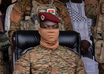 Burkina Faso military leader in camouflage uniform seated among armed soldiers during official address